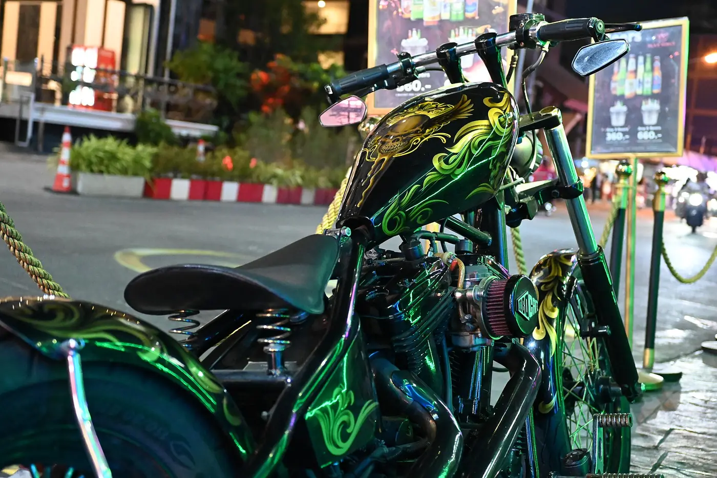 Custom chopper motorcycle with green candy paint and gold flame artwork across the tank and frame