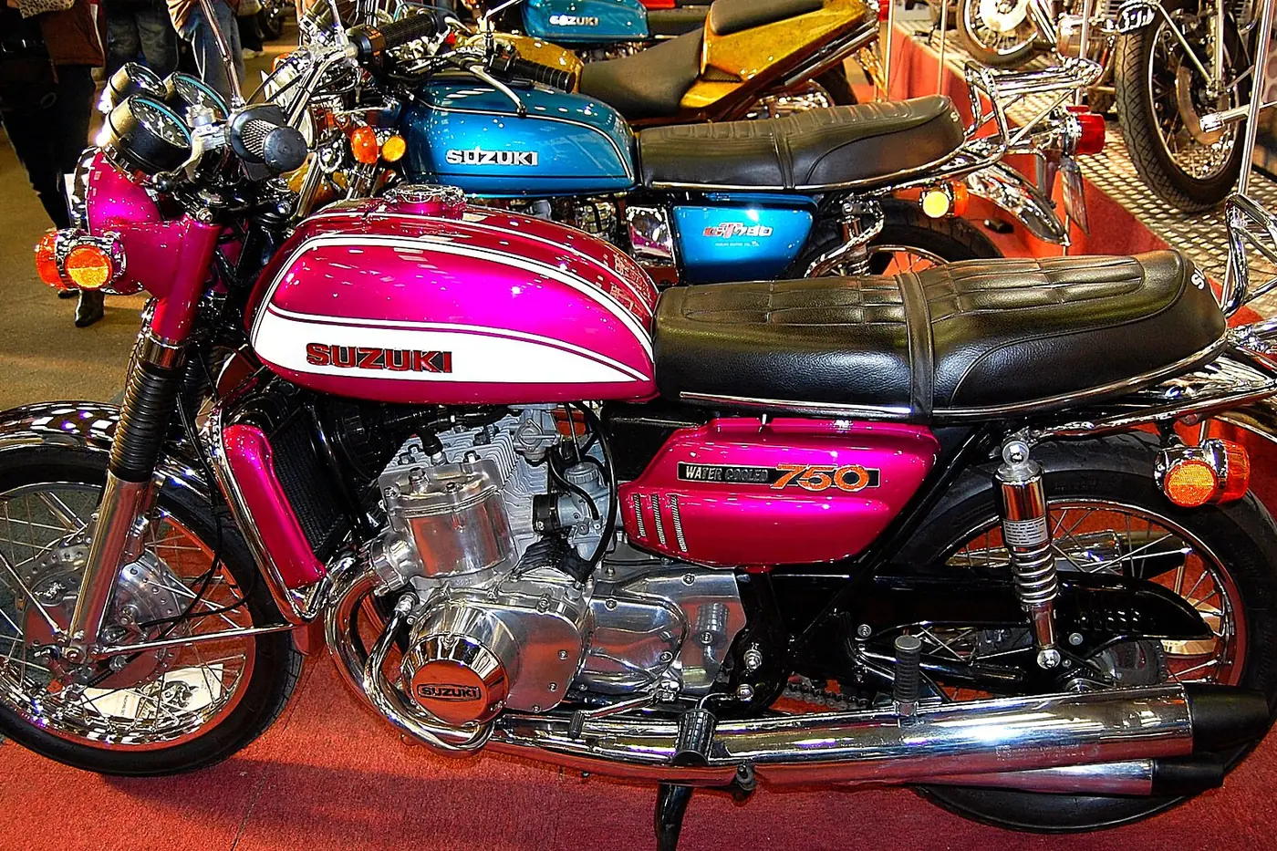 Vintage Suzuki GT750 motorcycle with a candy pink tank and side panels at a show