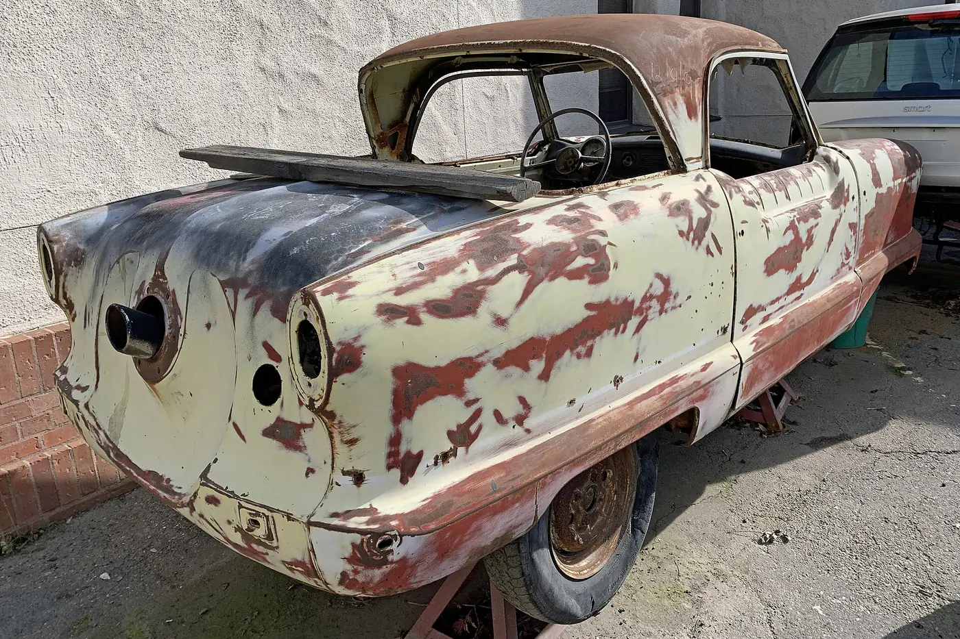 Classic car body with patches of old paint, primer and rust showing during restoration